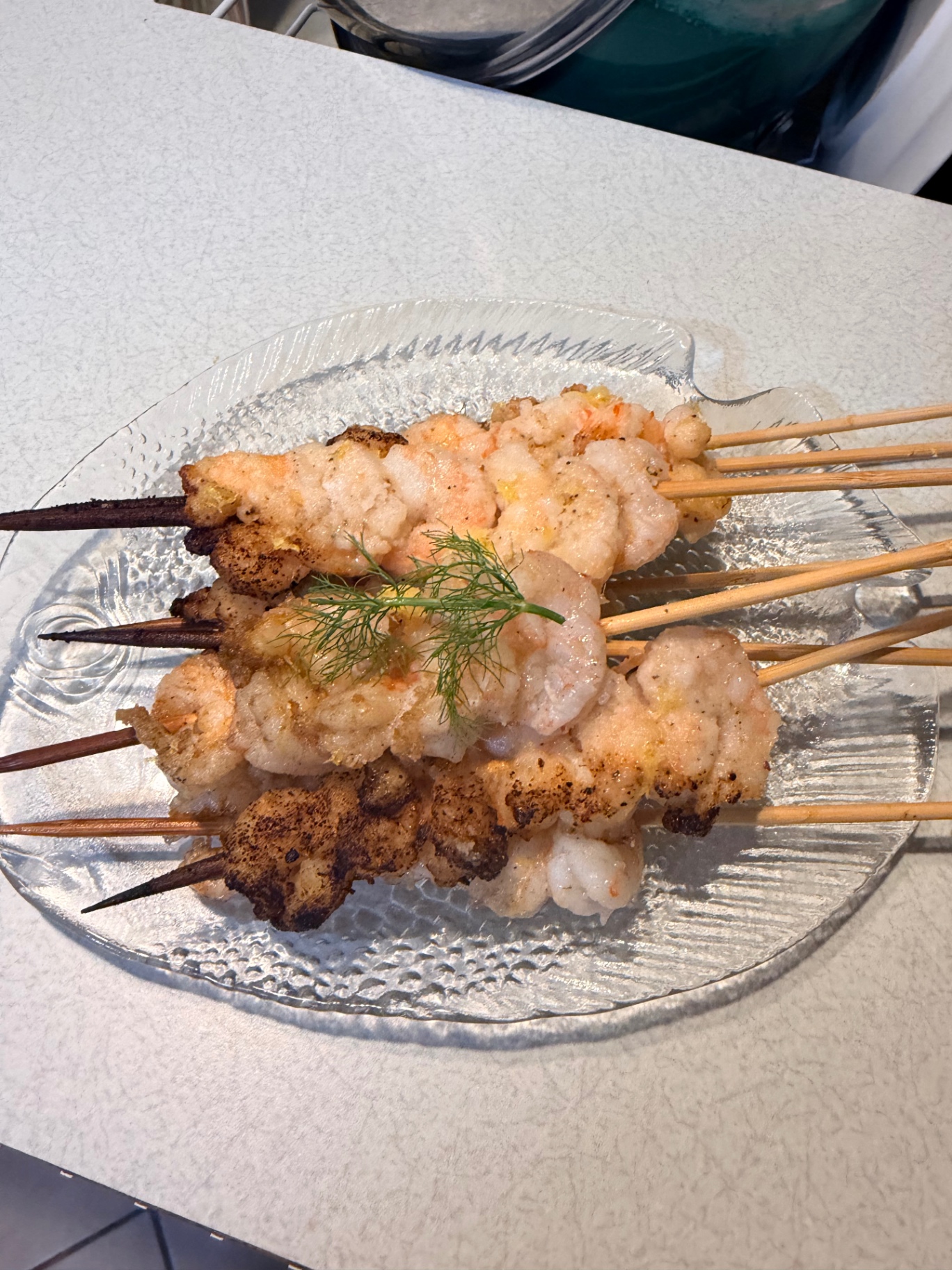 Grilled shrimp skewers served on a glass platter